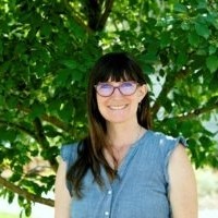 Photo of Amy May in blue shirt and red glasses