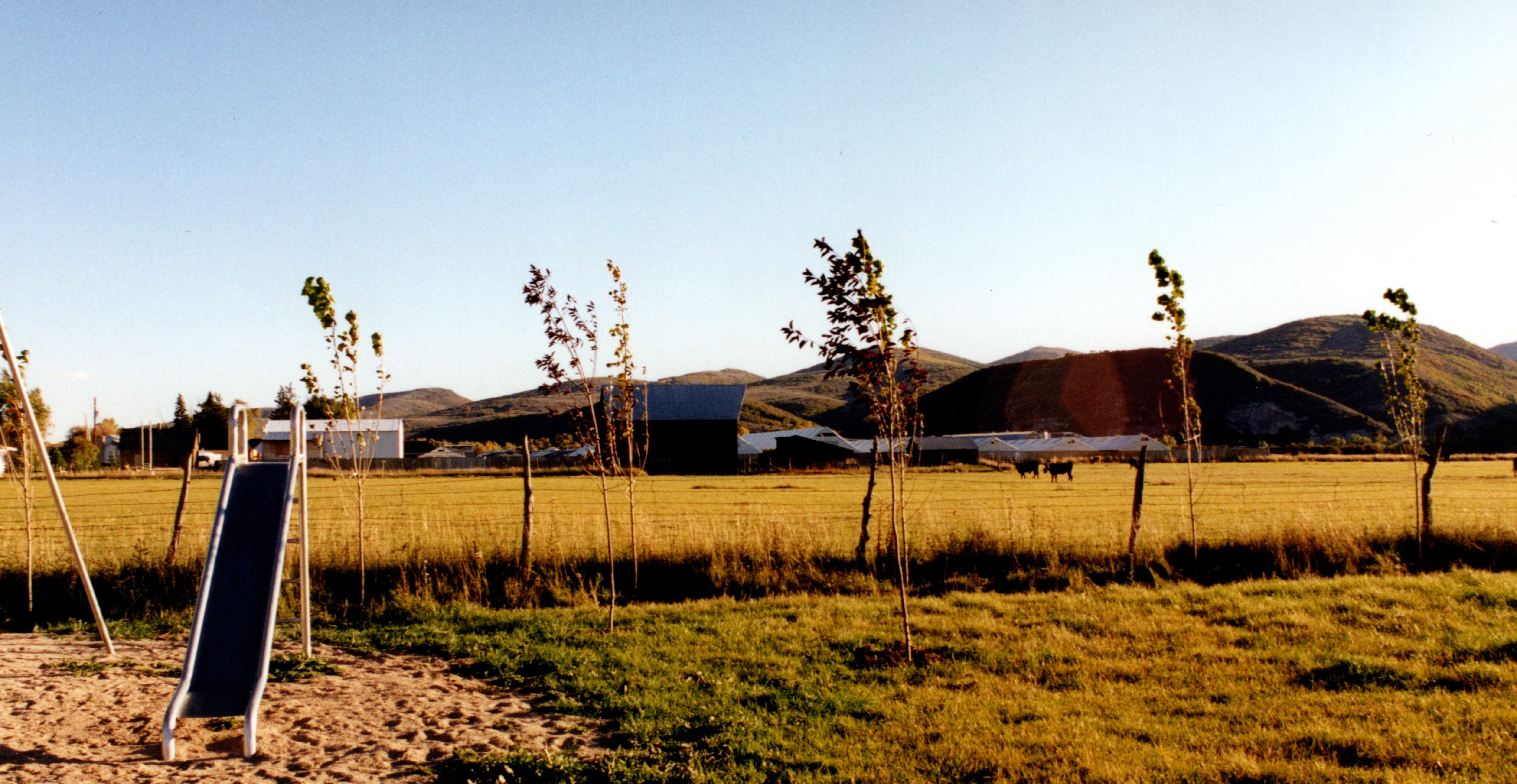 Metal slide in park with trees and hills in sunlight