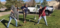 Threevolunteers begin digging a hole in a grassy field